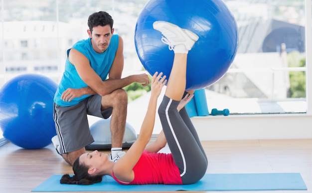 Trener pomaga kobieta z jej ćwiczeniami przy gym