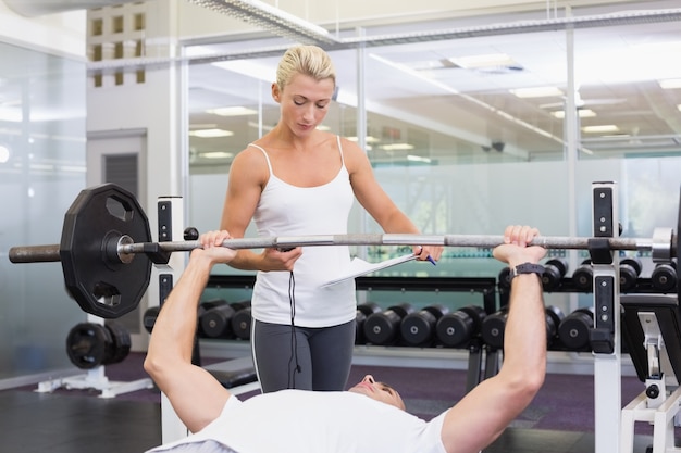 Trener Pomaga Mężczyzna Z Podnośnym Barbell W Gym