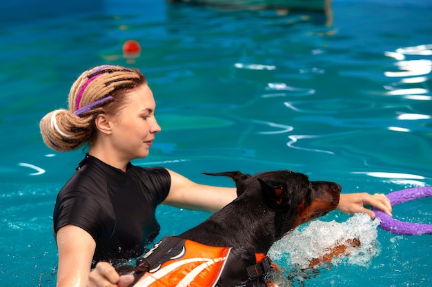 Trener psów na basenie uczy psa pływać