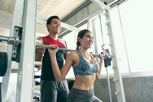 Trener z azjatykciej kobiety podnośnym barbell w gym.