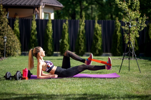 Trenerka fitness robi telefoniczny blog wideo na temat treningu i używania gumy fitness