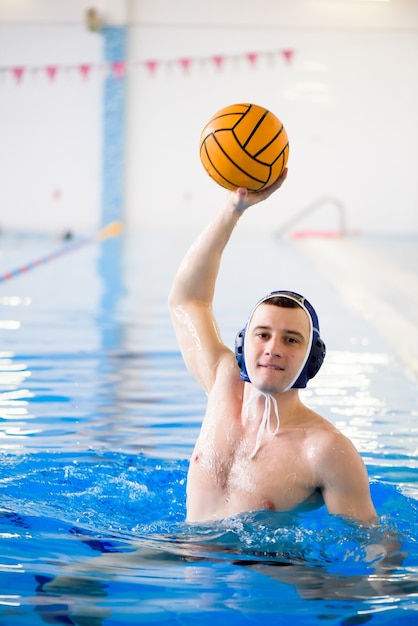 Trening piłki wodnej. Młody sportowiec gra w piłkę wodną w basenie.