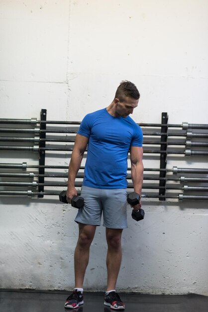 trening siłowy fitness człowiek wewnątrz wypracowania broni hantle robi biceps loki. Męski model sportowy ćwiczenia w pomieszczeniu w ramach zdrowego stylu życia.