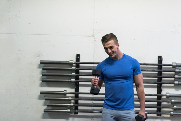 trening siłowy fitness człowiek wewnątrz wypracowania broni hantle robi biceps loki. Męski model sportowy ćwiczenia w pomieszczeniu w ramach zdrowego stylu życia.