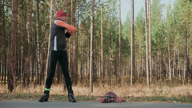 Trening sportowca na wrotkach Biathlon jazda na wrotkach z kijkami w kasku Jesienny trening Sport na rolkach Dorosły mężczyzna jeżdżący na łyżwach Sportowiec wykonuje trening Zwolnione tempo