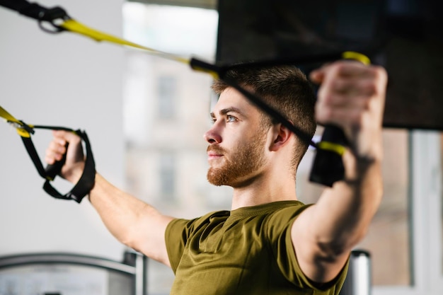 Trening trx młody człowiek sportowy w siłowni