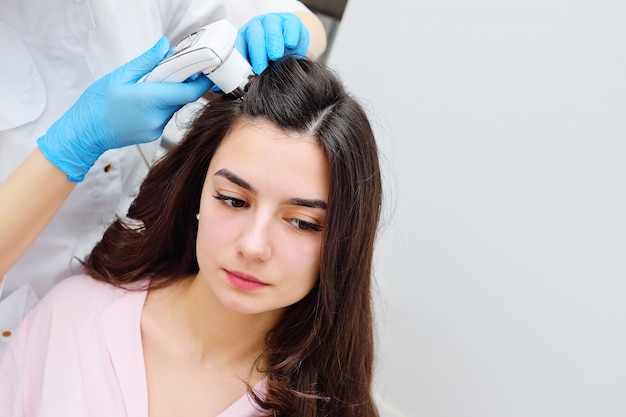 Tricholog dermatolog dokonuje komputerowej diagnozy stanu włosów atrakcyjnego pacjenta dla młodej kobiety