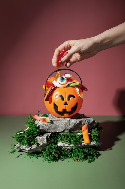 Trick or treat Pumpkin Jack wypełniony różnymi przerażającymi słodyczami stoi na kamieniach i mchu