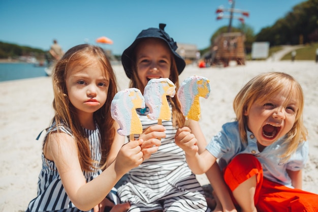 Troje dzieci je lody na plaży, dziecko z zespołem Downa prowadzi normalne życie