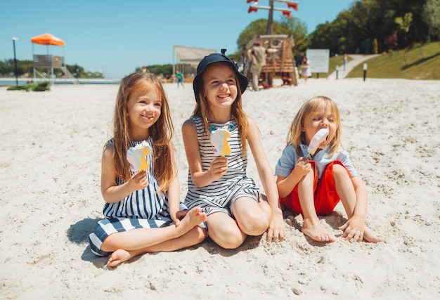 Troje dzieci je lody na plaży, dziecko z zespołem Downa prowadzi normalne życie