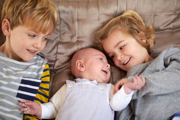 Zdjęcie troje dzieci leżących na łóżku chłopiec i dziewczynka z dzieckiem między nimi