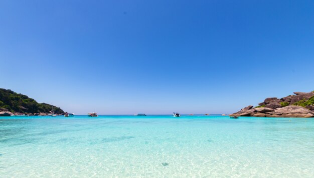 Tropikalne plaże mają ciepłą, czystą, błękitną wodę i błękitne niebo w tle lub scenerię na wyspach Similan