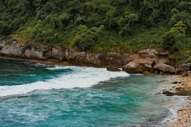 tropikalne tło, plaża z błękitną wodą, fale łamią się na kamieniu