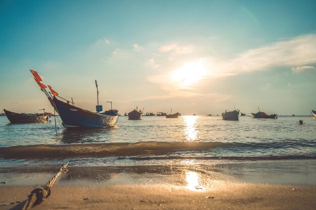 Tropikalny pejzaż morski z łodzią na piaszczystej plaży przy pochmurnym wschodzie lub zachodzie słońca Piękny zachód słońca tropikalna plaża z małą łódką i kinowym niebem do podróży i wakacji w wakacyjnym czasie relaksu