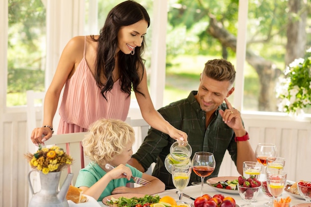 Troskliwa mama nalewa lemoniadę dla swojego uroczego blond syna