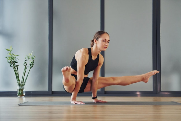 Trudne ćwiczenie Młoda kobieta w sportowej odzieży i szczupłej sylwetce ma dzień jogi fitness w pomieszczeniu