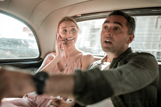 Zdjęcie trudny sposób. zmartwiony mężczyzna siedzący z żoną na tylnym siedzeniu samochodu i wyjaśniający kierowcy, gdzie jechać, wskazując na drogę.