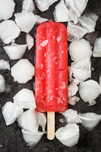 Zdjęcie truskawkowy popsicle i lód na czerń kamieniu