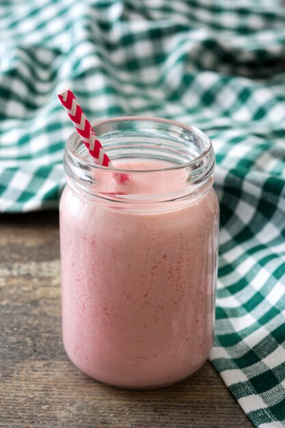 Truskawkowy smoothie w szkle na drewnianym stole