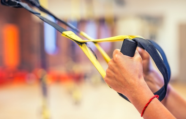 TRX. Kobiece ręce z paskami fitness TRX w siłowni.