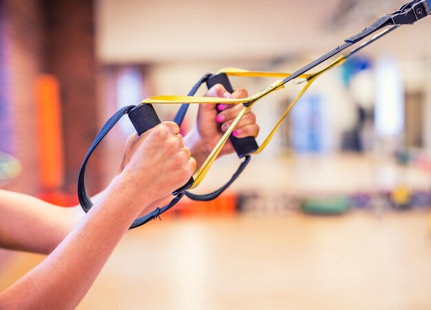 TRX. Kobiece ręce z paskami fitness TRX w siłowni.