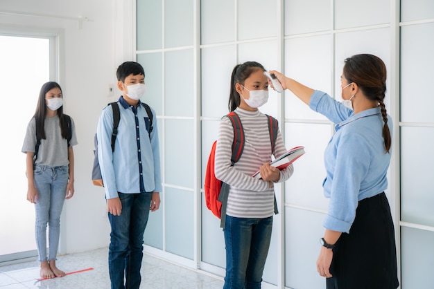 Trzech azjatyckich studentów noszących maskę w odległości 6 stóp od innych ludzi zachowuje dystans