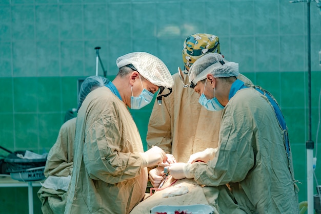 Trzech lekarzy przeprowadza operację pacjenta z udziałem pielęgniarki na sali operacyjnej