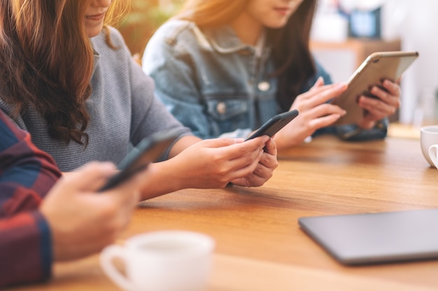 Trzech młodych azjatyckich ludzi używających i patrzących na telefon komórkowy i tablet PC