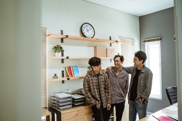 Trzech młodych azjatyckich pracowników rozmawiających o swoim produkcie