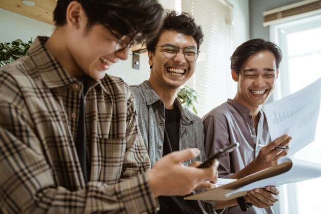 Trzech młodych azjatyckich pracowników rozmawiających o swoim produkcie