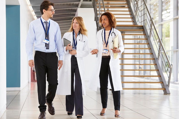 Zdjęcie trzech młodych lekarzy płci męskiej i żeńskiej spacerujących w szpitalu