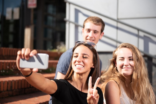 Trzech szczęśliwych studentów uśmiecha się i robi selfie