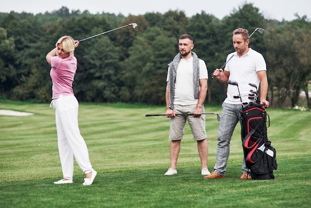 Zdjęcie trzej przyjaciele spędzają miło czas na boisku, grając w golfa i oglądając strzał.