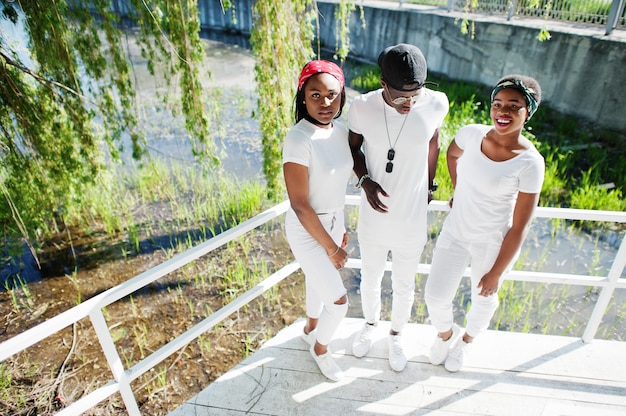 Trzej Stylowi I Modni Przyjaciele Z Afryki, Noszą Białe Ubrania. Moda Uliczna Młodych Czarnych Ludzi. Murzyn Z Dwoma Afrykańskimi Dziewczynami.