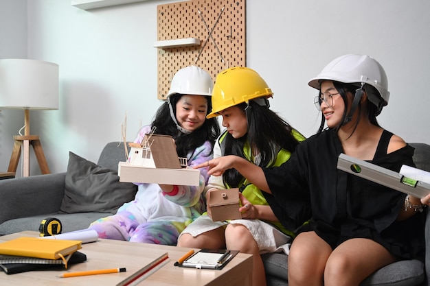Trzy Azjatki w kaskach udają inżyniera podczas wspólnej zabawy w salonie