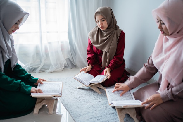 Trzy azjatyckie muzułmanki razem czytają i uczą się świętej księgi Al-Koranu