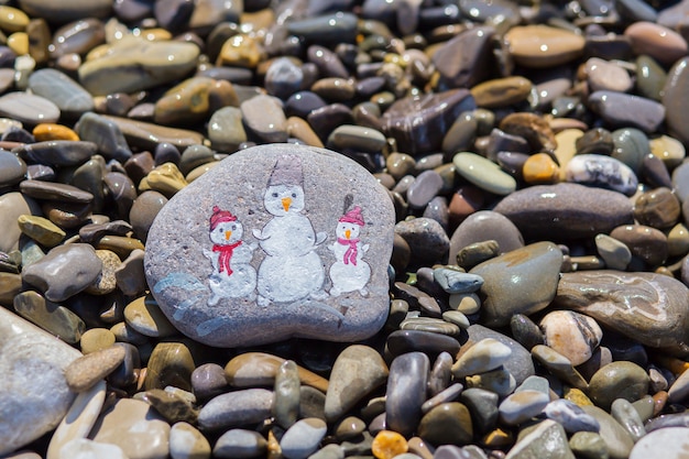 Trzy bałwany malowane akwarelą na kamienistej plaży nad morzem