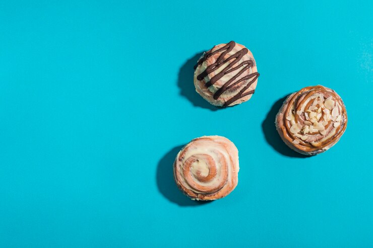 Trzy bułeczki Cinnabon na niebieskim tle z twardymi cieniami. Amerykańska klasyczna bułka.