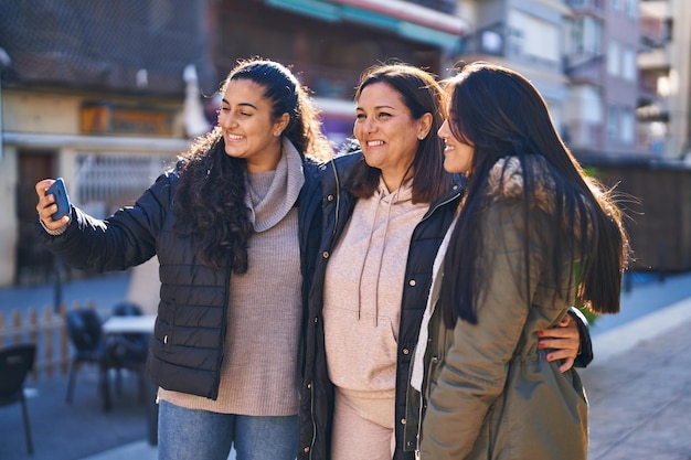 Trzy kobiety matka i córki robią selfie smartfonem na ulicy