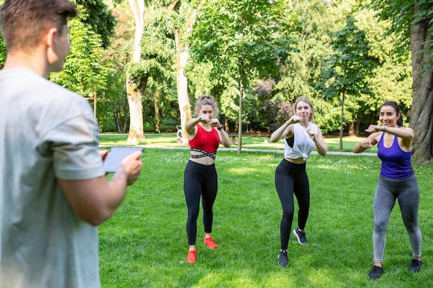 Trzy kobiety pracują w parku z ich męskim trenerem crossfit