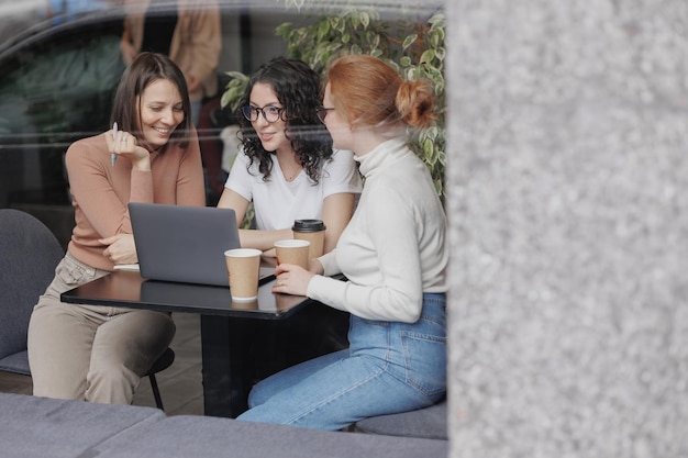 Trzy koleżanki lub studentki pracują na laptopie i omawiają projekt lub kreatywność