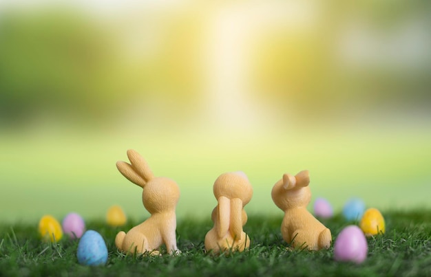 Trzy króliczki wielkanocne siedzące na trawie z tyłu wśród zdobionych jajek i spójrz na miejsce na tekst