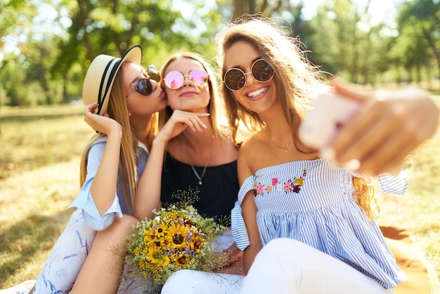 Trzy ładne dziewczyny dobrze się bawią W parku i robią selfie Doskonała słoneczna pogoda Piękne figury