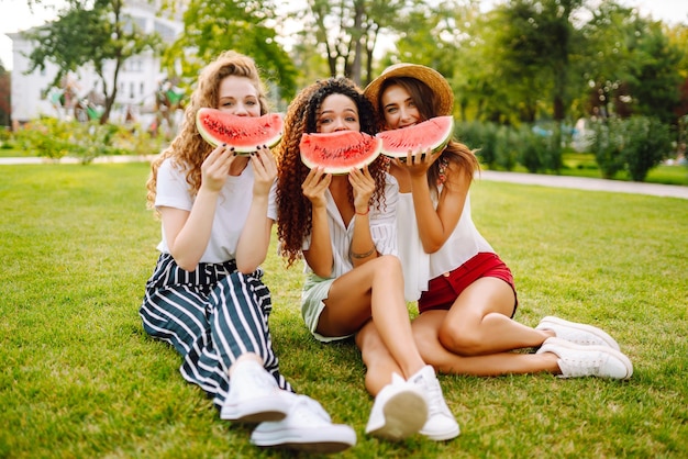Trzy młode kobiety bawią się razem i jedzą arbuzy w gorący letni dzień