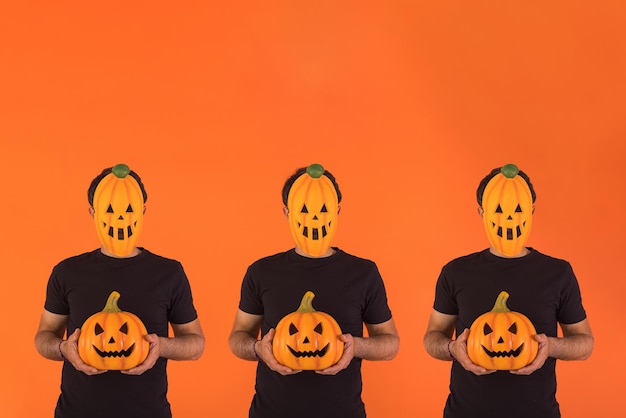 Zdjęcie trzy osoby z maską dyni świętują halloween trzymając dynię na pomarańczowym tle koncepcja świętowania dzień zaduszny39 i dzień wszystkich świętych39