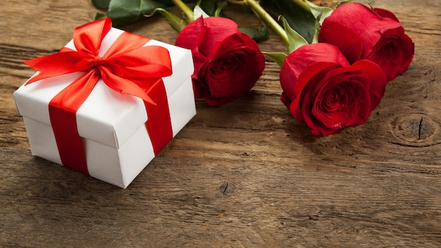 Trzy piękne czerwone róże leżą na drewnianej powierzchni