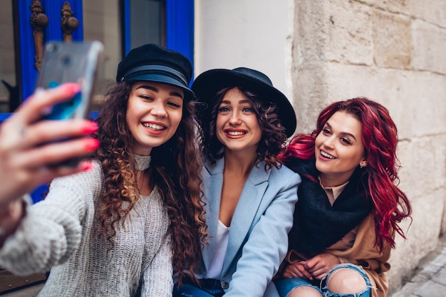 Trzy piękne kobiety przy selfie na ulicy miasta. Szczęśliwi przyjaciele wiszą i bawią się na świeżym powietrzu