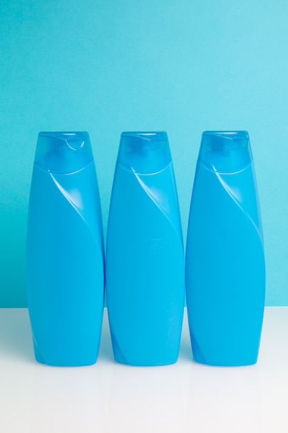 Trzy plastikowa butelka z szamponem na błękitnym tle