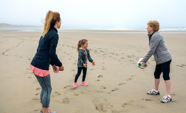 Trzy pokolenia kobiet bawiących się jesienią na plaży