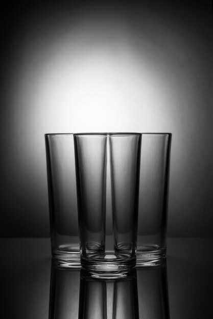 Trzy puste szklanki na czarno-białym tle z odbiciem